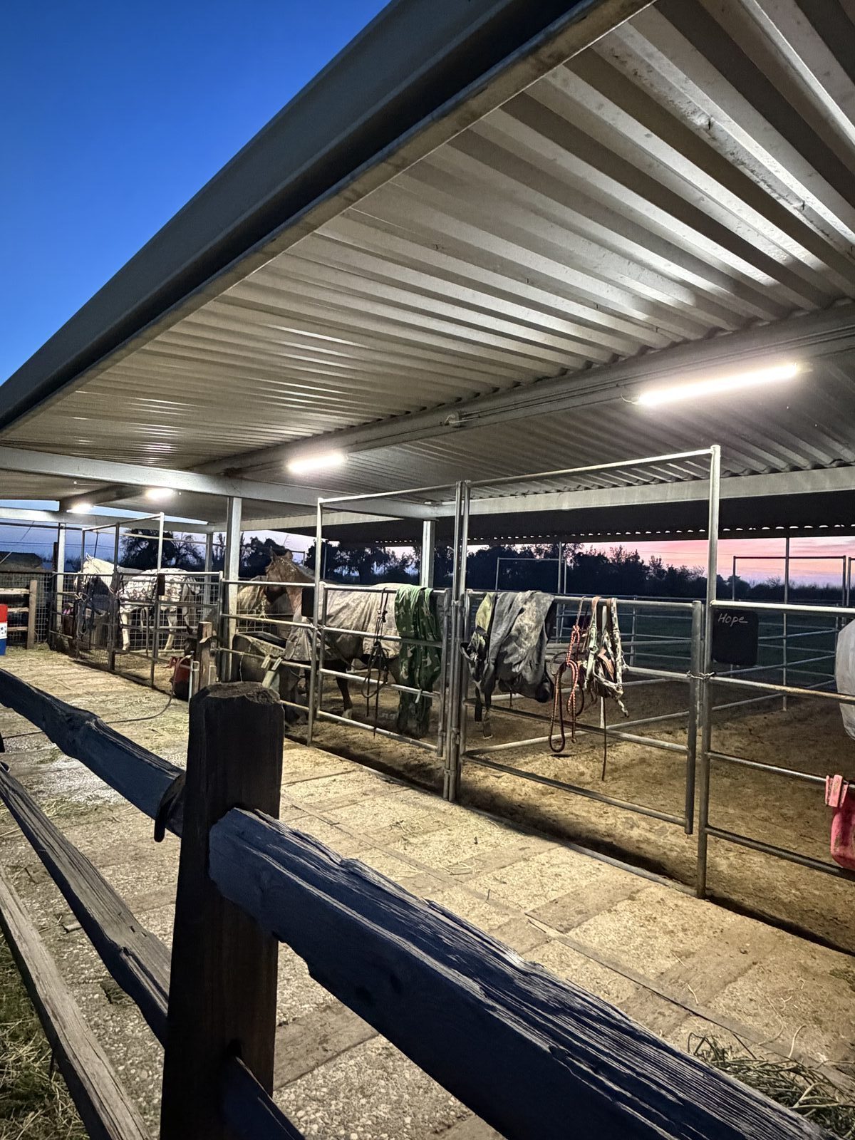 Interior view of horse stable with LED strip lights mounted under metal roof framing — Cyber Electric LLC