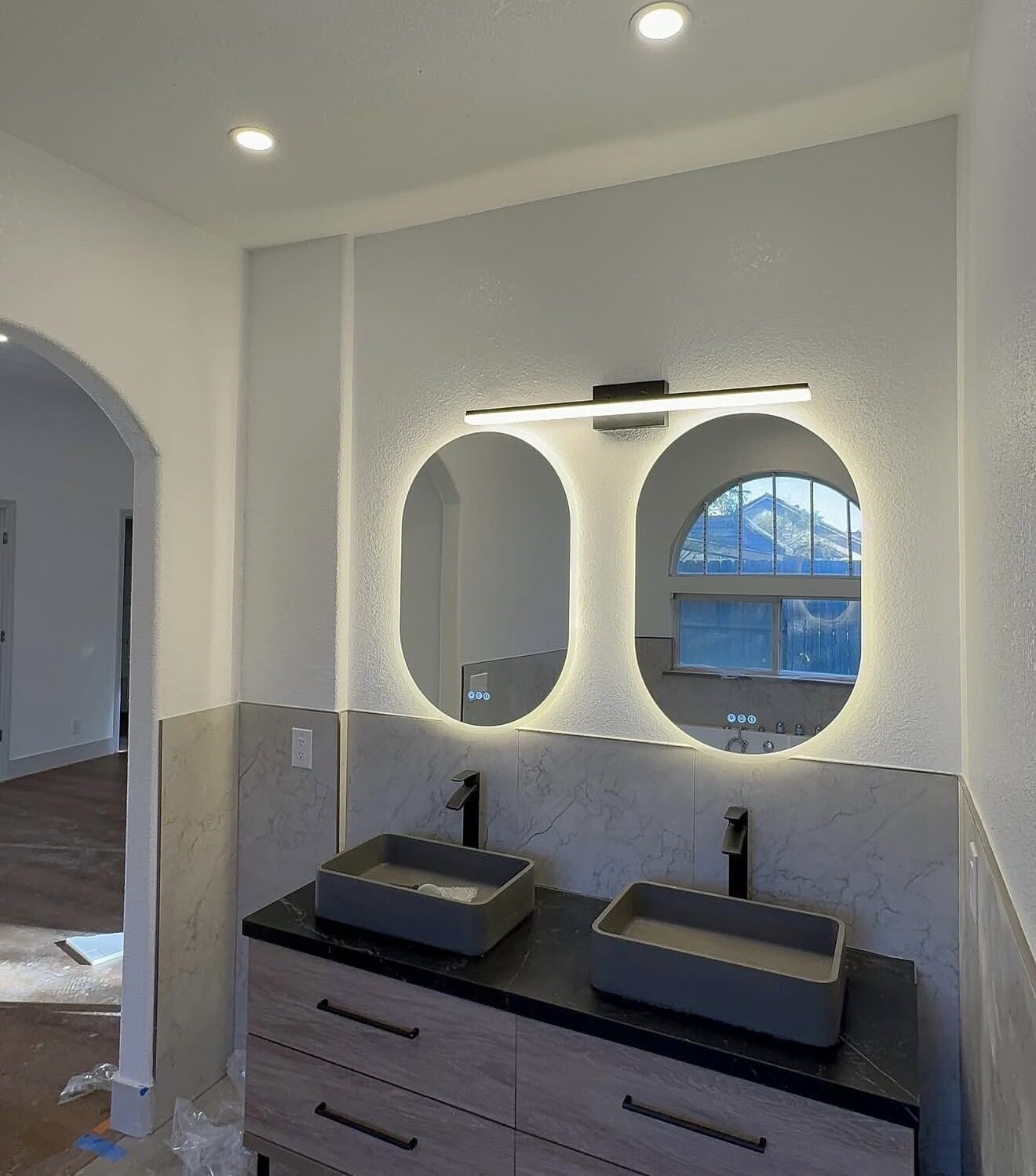 Secondary bathroom with dual oval backlit LED mirrors, vanity bar, and floating vanity — Cyber Electric LLC