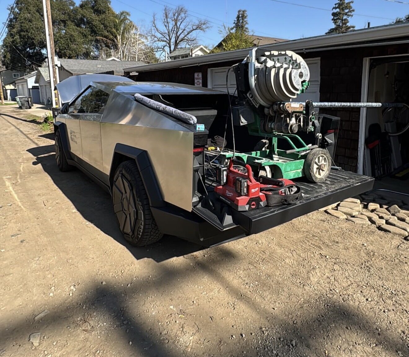 Tesla Cybertruck work truck with wire reel and Milwaukee tools loaded in the bed on the job site — Cyber Electric LLC