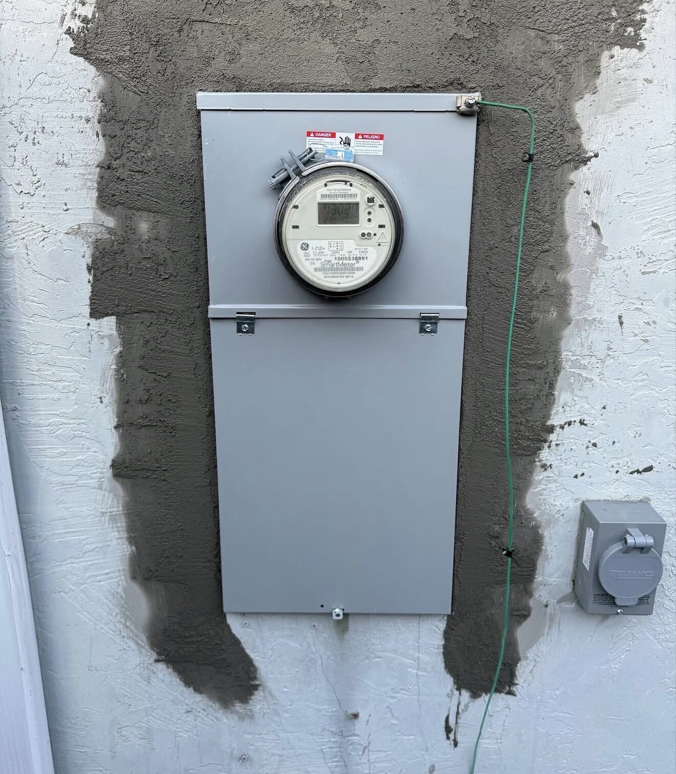 Finished panel replacement — new meter-main on stucco wall with fresh patch and generator inlet box — Cyber Electric LLC, Stockton CA